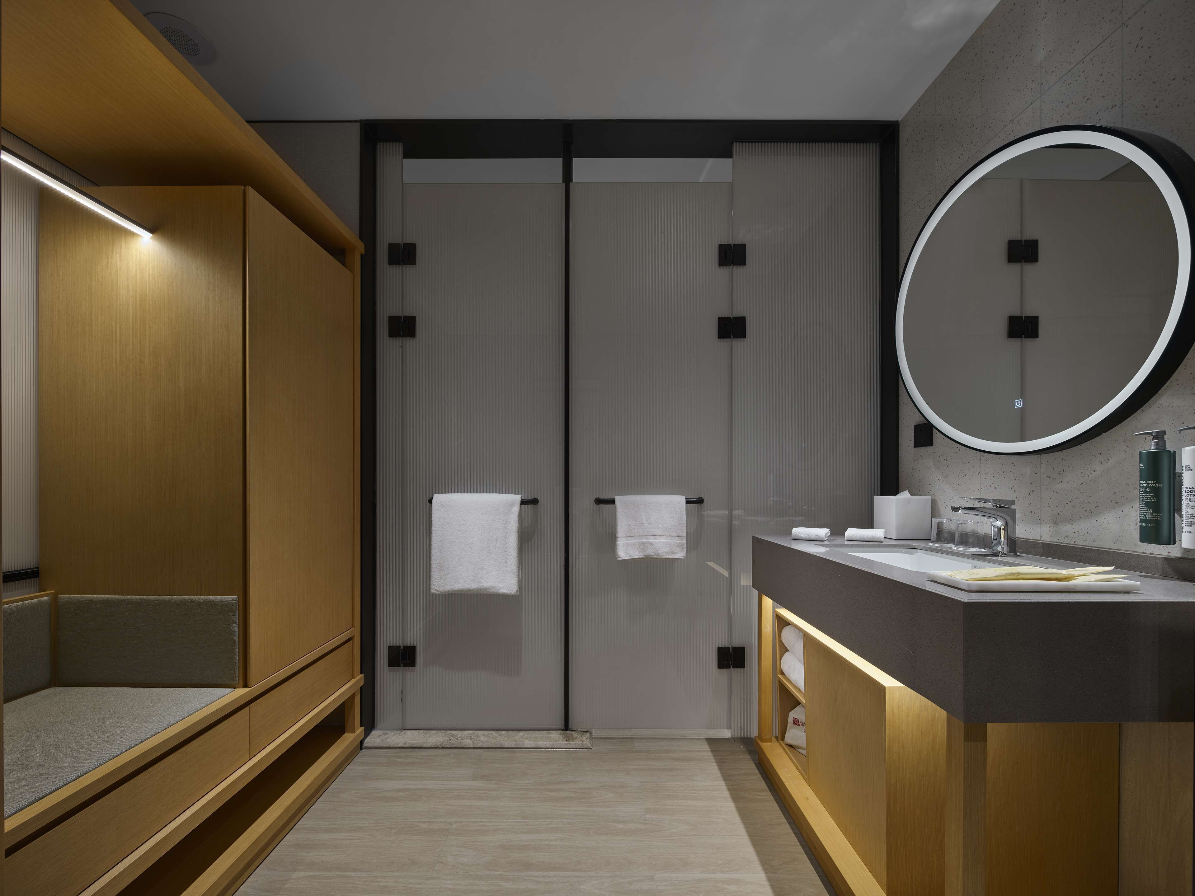 A modern bathroom with a wooden vanity, a large mirror, and a towel rack.