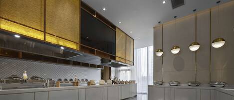 A modern kitchen with a long countertop, stainless steel appliances, and pendant lighting.