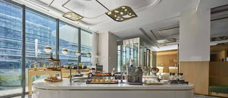 Un área de cocina moderna con una isla central, ventanas amplias e iluminación contemporánea.