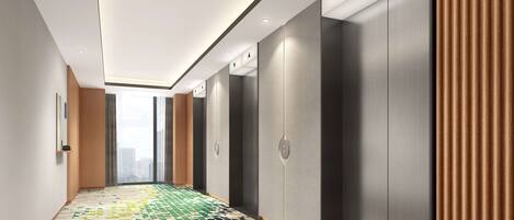 A modern hallway with patterned flooring, recessed lighting, and a view of a cityscape through large windows.