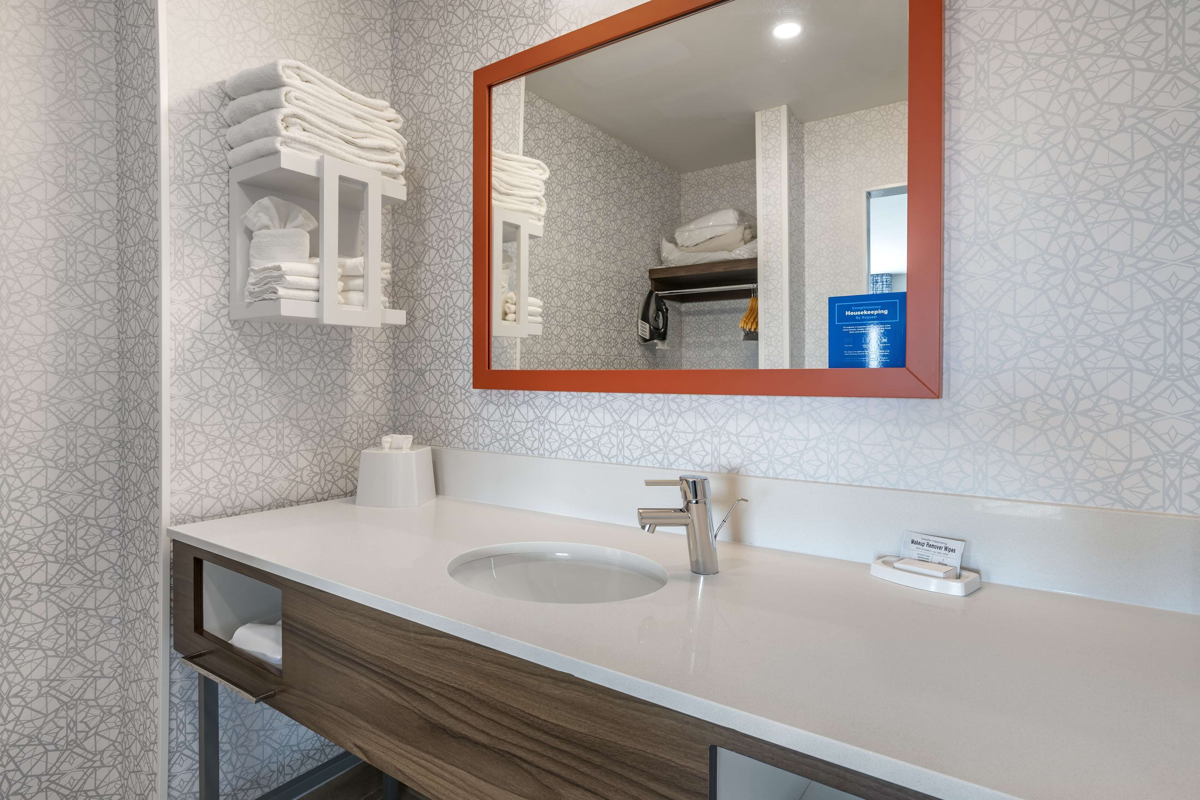 A modern bathroom with a large mirror, a sink, and towel racks.