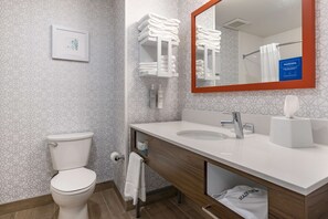Une salle de bain moderne avec des toilettes, un lavabo et un miroir. On peut voir des serviettes et des articles de toilette.