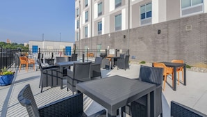 An outdoor patio area with tables and chairs, a brick wall, and a clear sky. - Hampton Inn Nicholasville Brannon Crossing (Nicholasville)