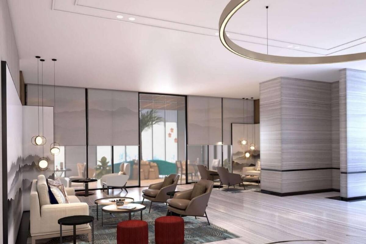 A modern living room with a sofa, armchairs, a coffee table, and a red ottoman.