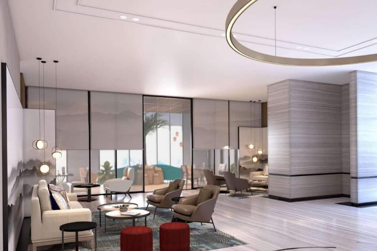A modern living room with a sofa, armchairs, a coffee table, and a red ottoman.