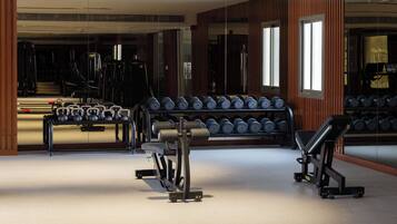 A gym with weightlifting equipment, a bench, and a mirrored wall.