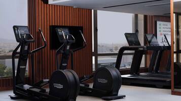 Un gimnasio con cintas de correr, elípticas y una máquina de remo.