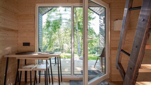 A wooden cabin interior with a sliding glass door leading to an outdoor deck.