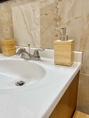Un lavamanos de baño con un grifo moderno y dos dispensadores de jabón de madera.
