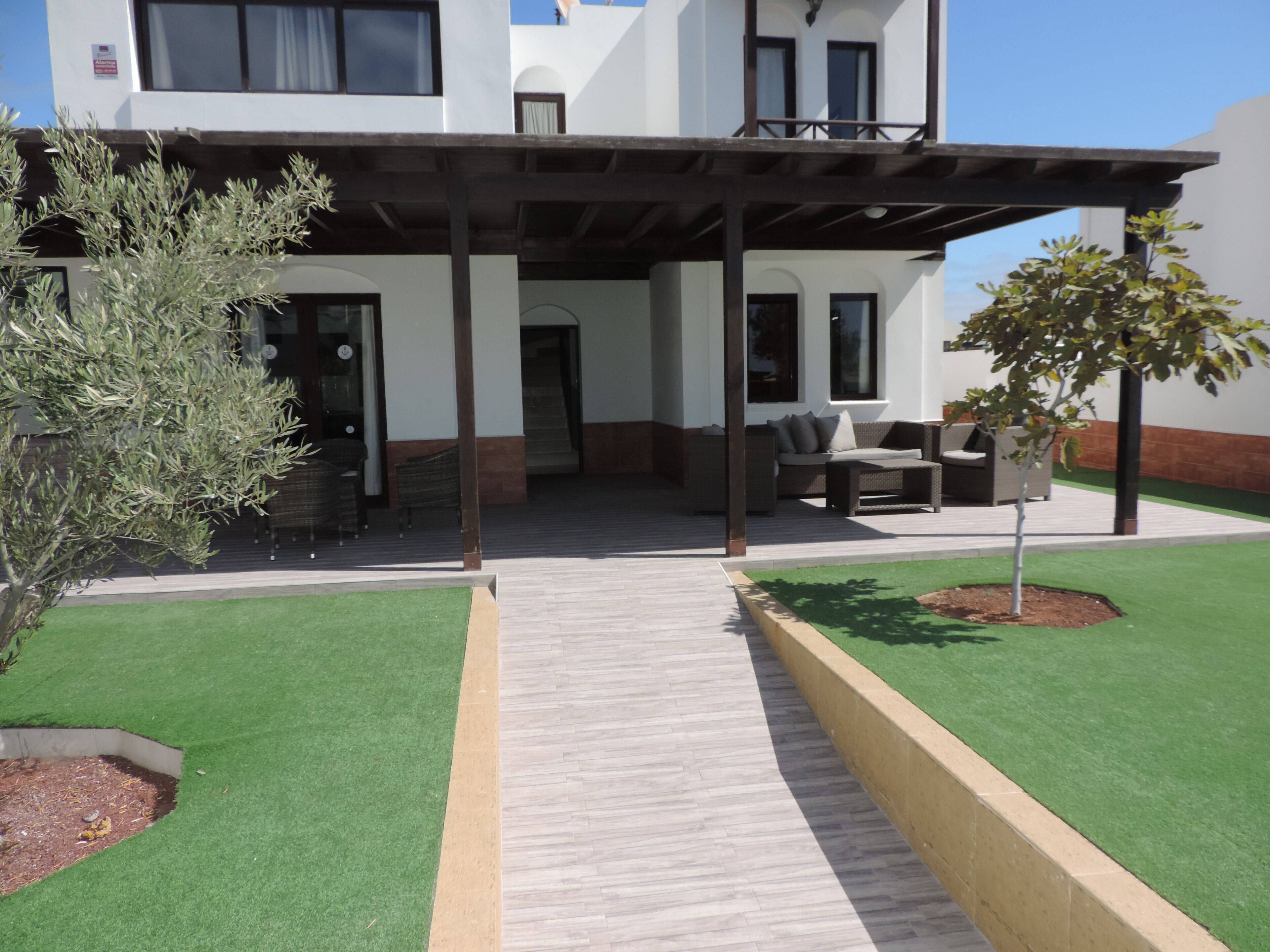 A modern building with a covered outdoor seating area and artificial grass.
