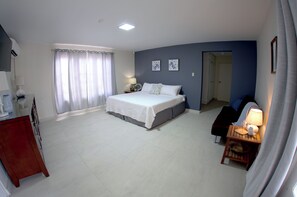 A bedroom with a bed, bedside table, lamp, and a view of a hallway.