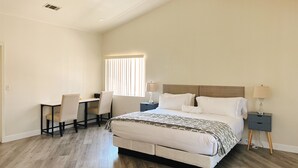 A bedroom with a bed, bedside tables, a desk, and a chair.
