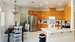 A modern kitchen with wooden cabinets, stainless steel appliances, and a white countertop.