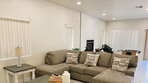 A living room with a sectional sofa, a glass coffee table, and a side table.