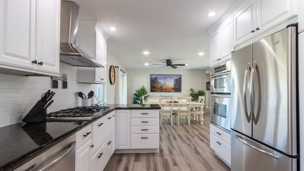 A modern kitchen with white cabinetry, stainless steel appliances, and a central island.