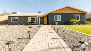 A modern two-story house with a paved driveway and outdoor lighting.