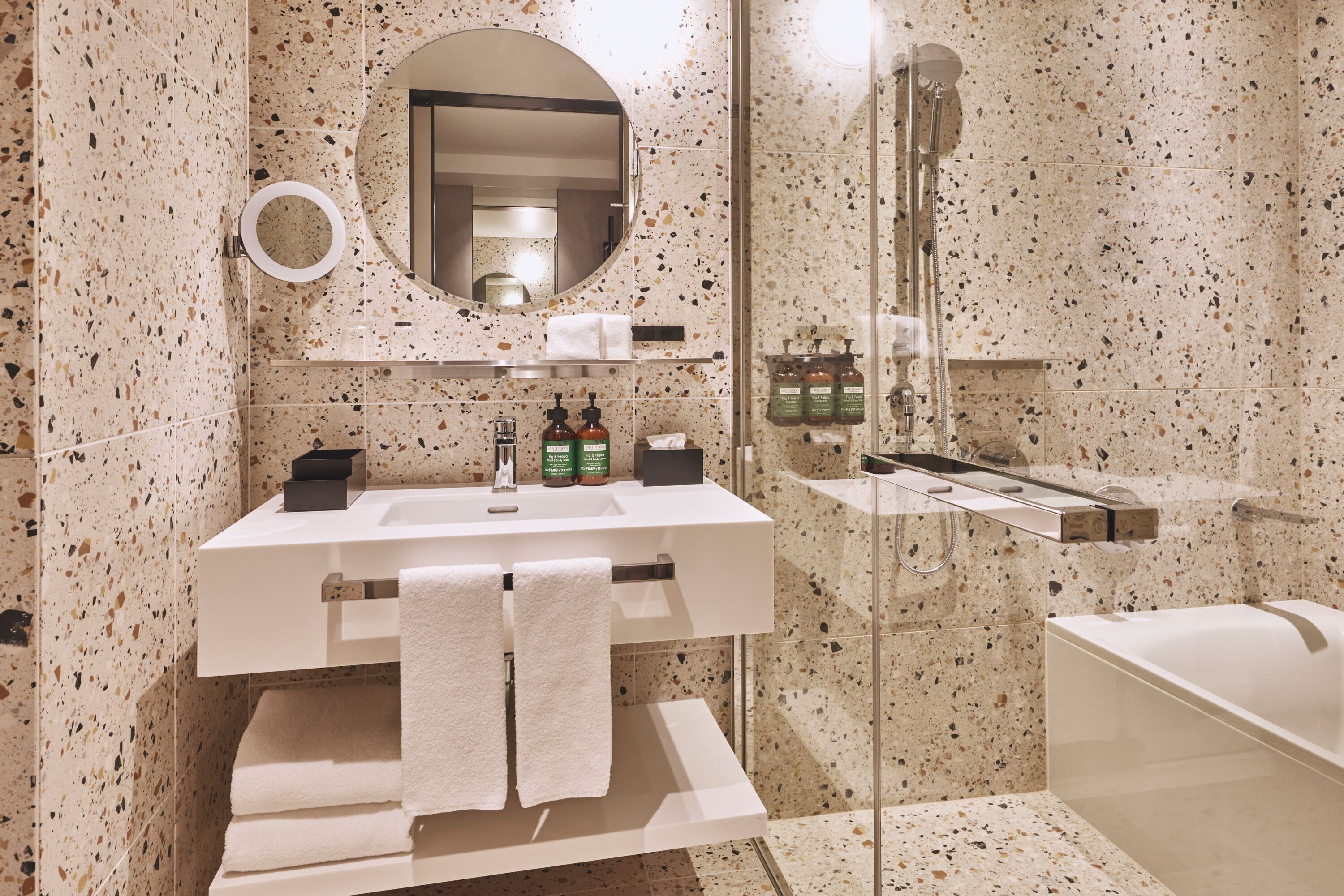A modern bathroom with a freestanding bathtub, a glass-enclosed shower, a vanity with a mirror, and a towel rack.