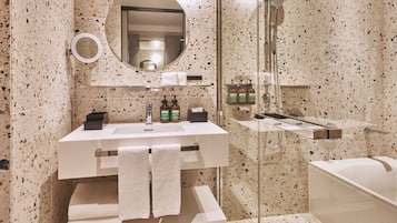 A modern bathroom with a freestanding bathtub, a glass-enclosed shower, a vanity with a mirror, and a towel rack.