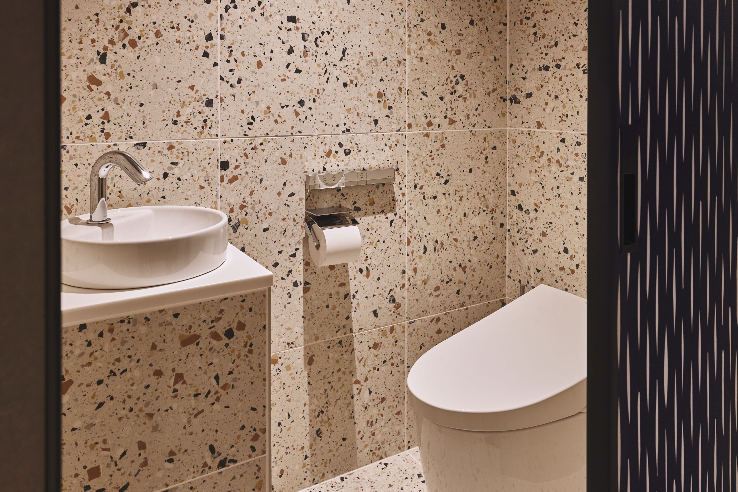 Un bagno con un lavandino bianco, un rubinetto moderno e un WC.