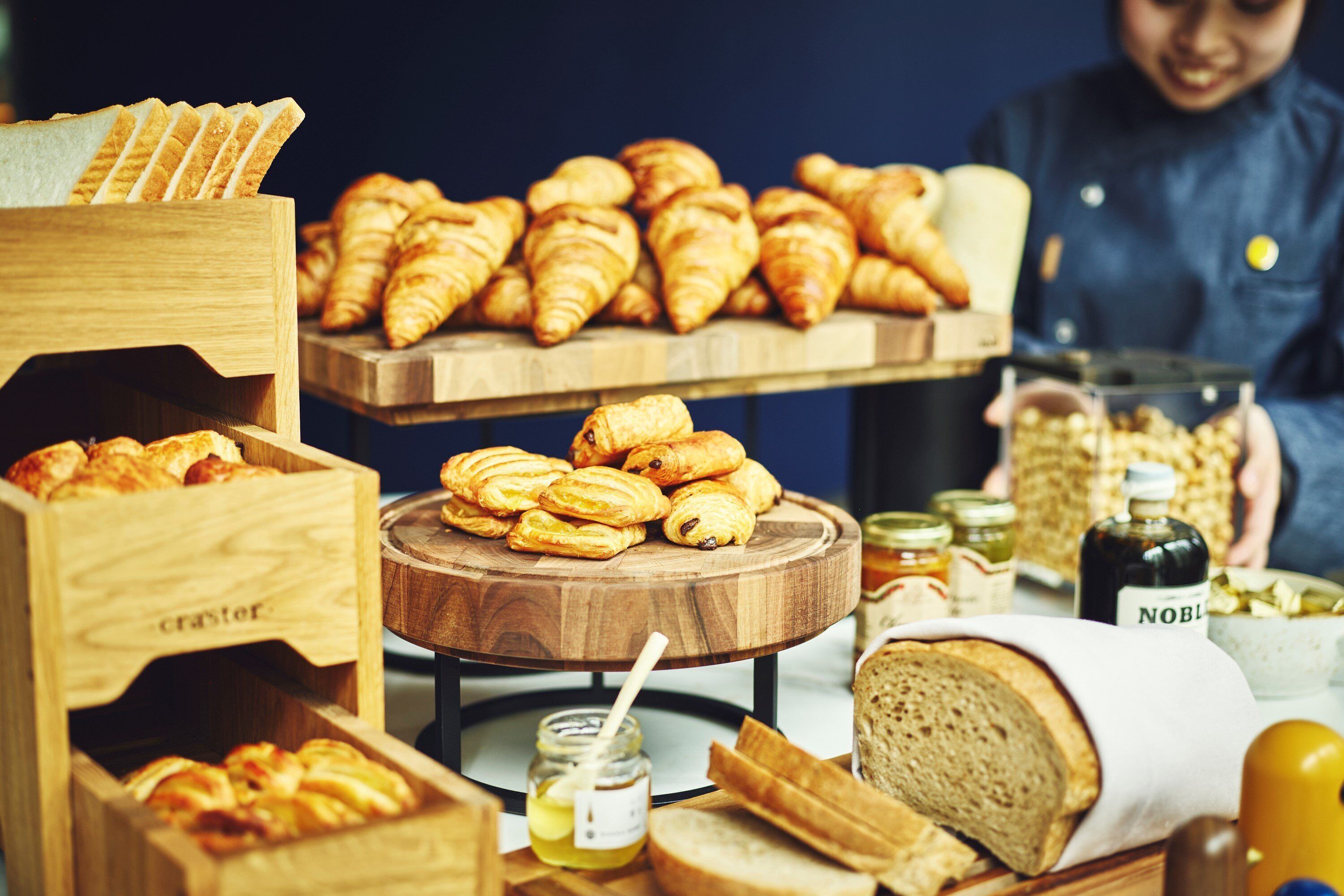 Una mesa de buffet con diversos productos horneados, como pan, pasteles y un tarro de miel.