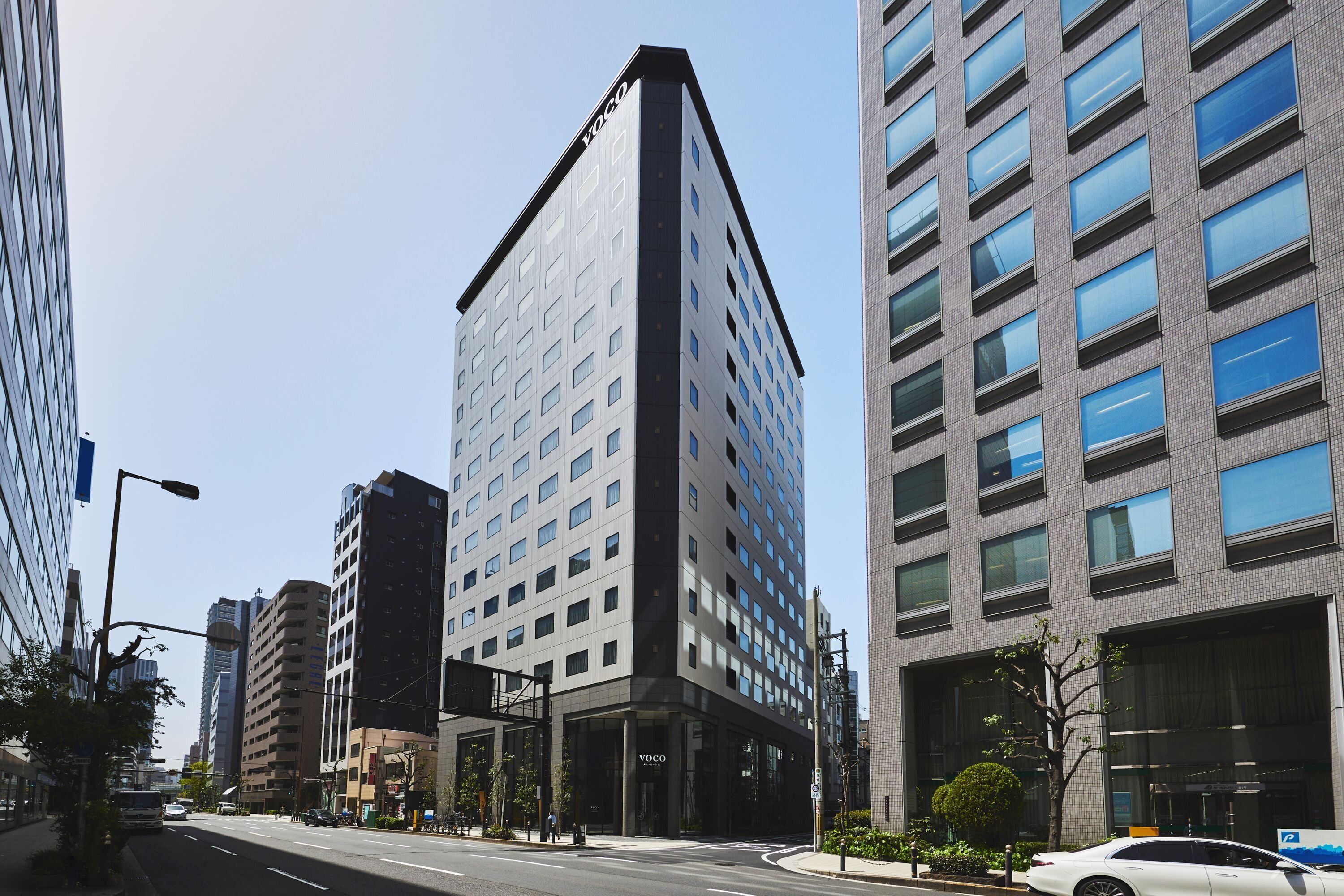 A modern building with a prominent entrance and a clear sky.