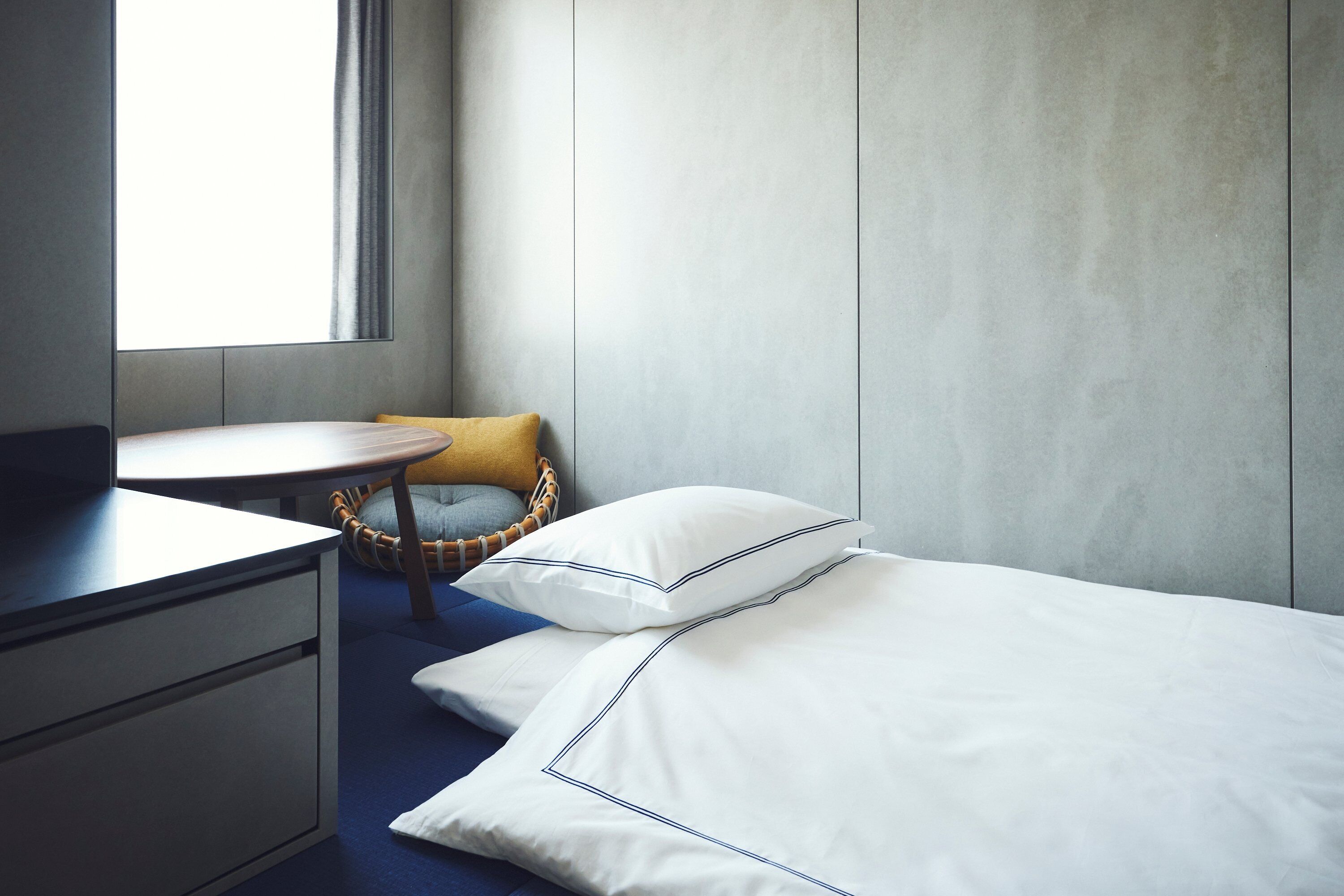 A hotel room with a bed, a desk, a chair, and a window.