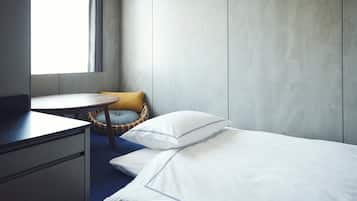 Una habitación de hotel con cama, escritorio, silla y ventana.