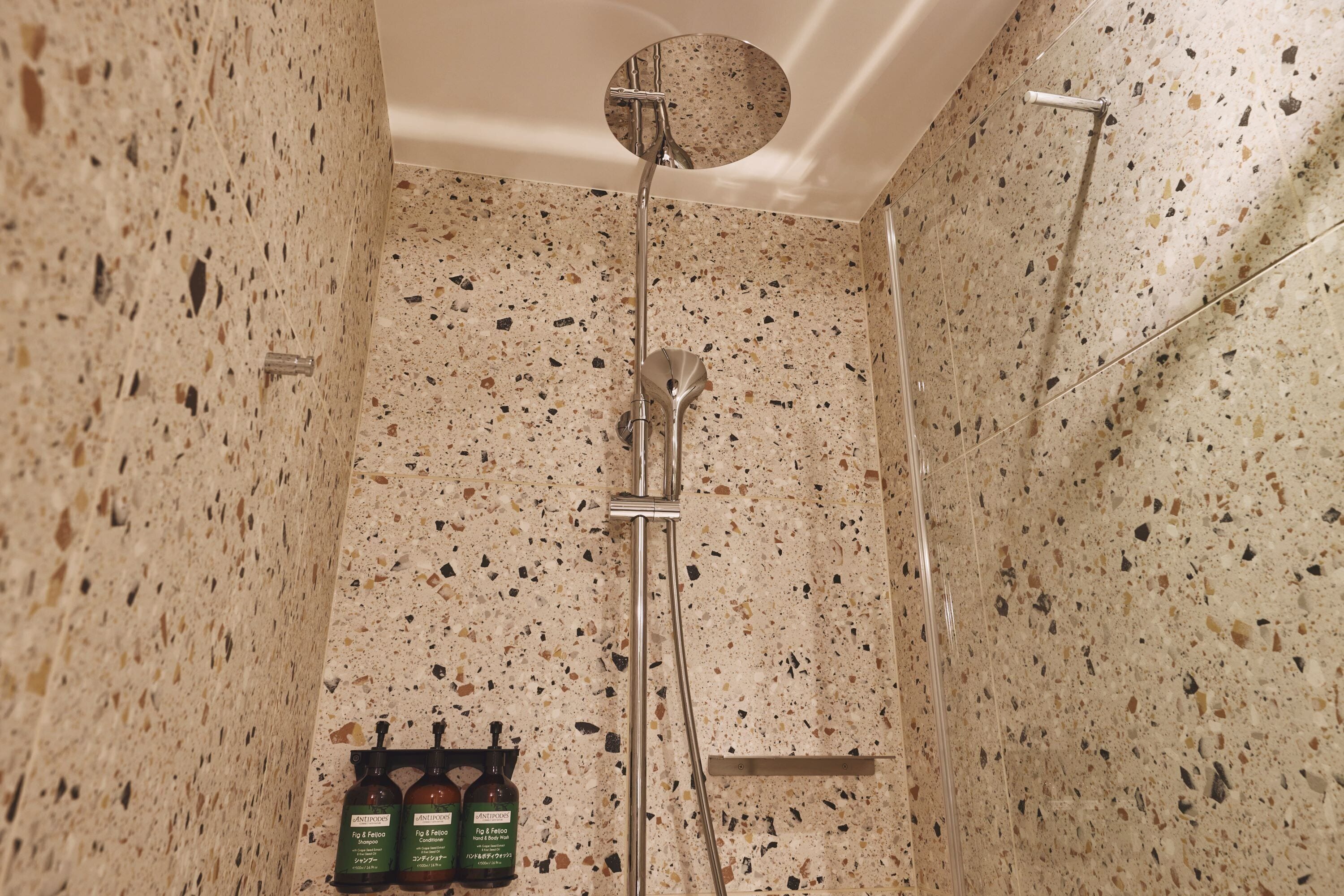 A shower with a circular ceiling design, a handheld showerhead, and a wall-mounted faucet.