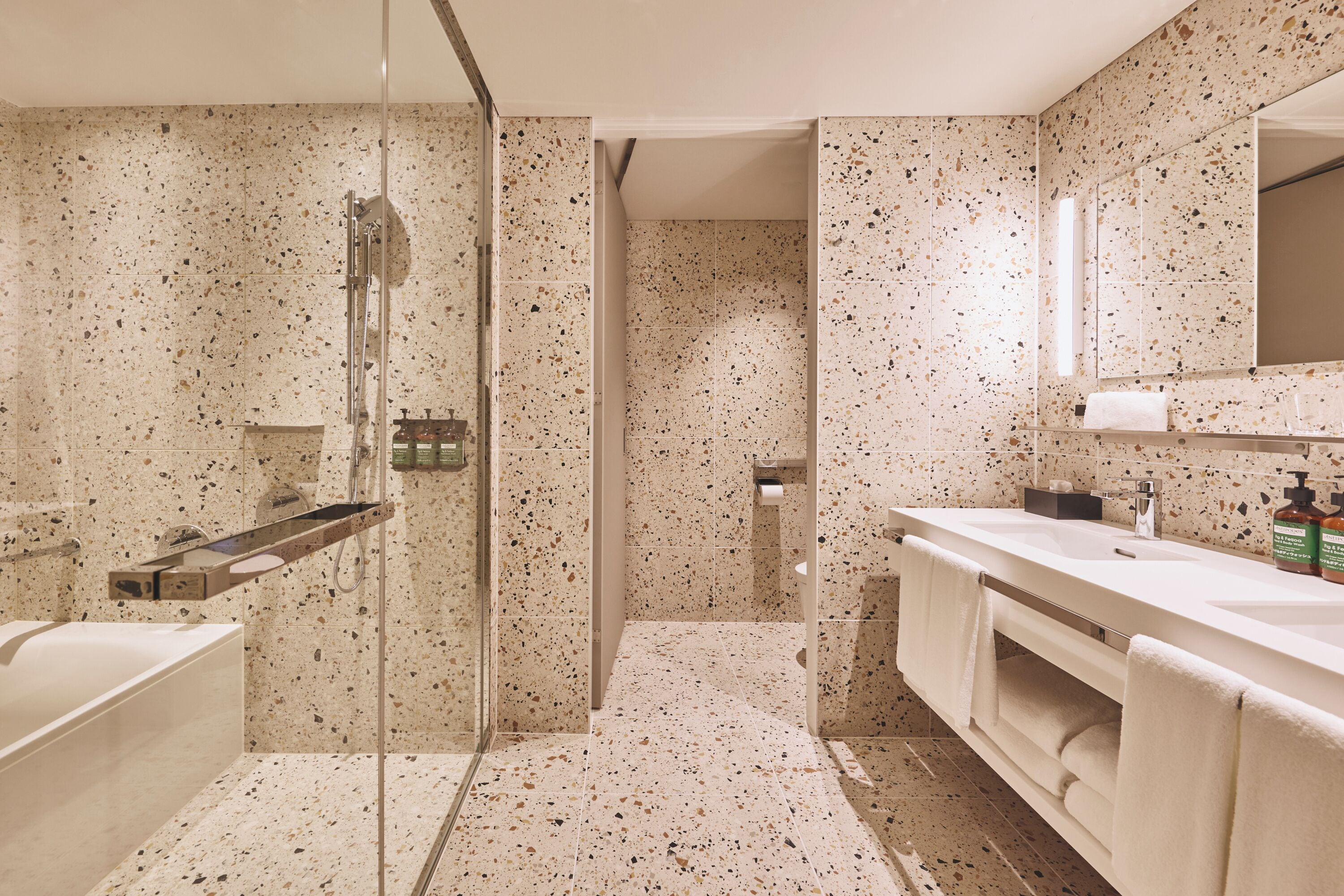Een moderne badkamer met een douchecabine van glas, een witte wastafel en een grote spiegel.