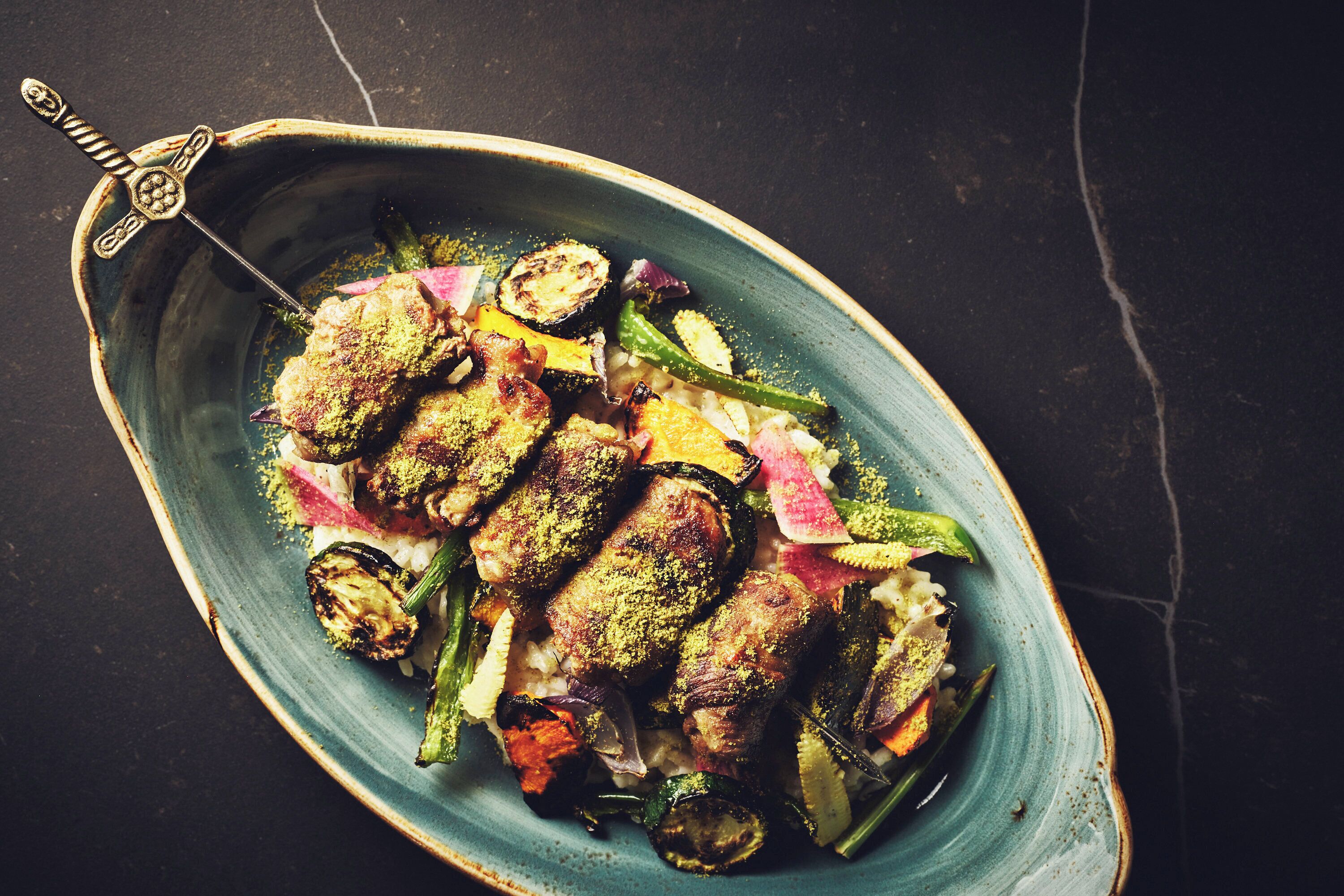 A dish with grilled meat and vegetables on a ceramic plate.