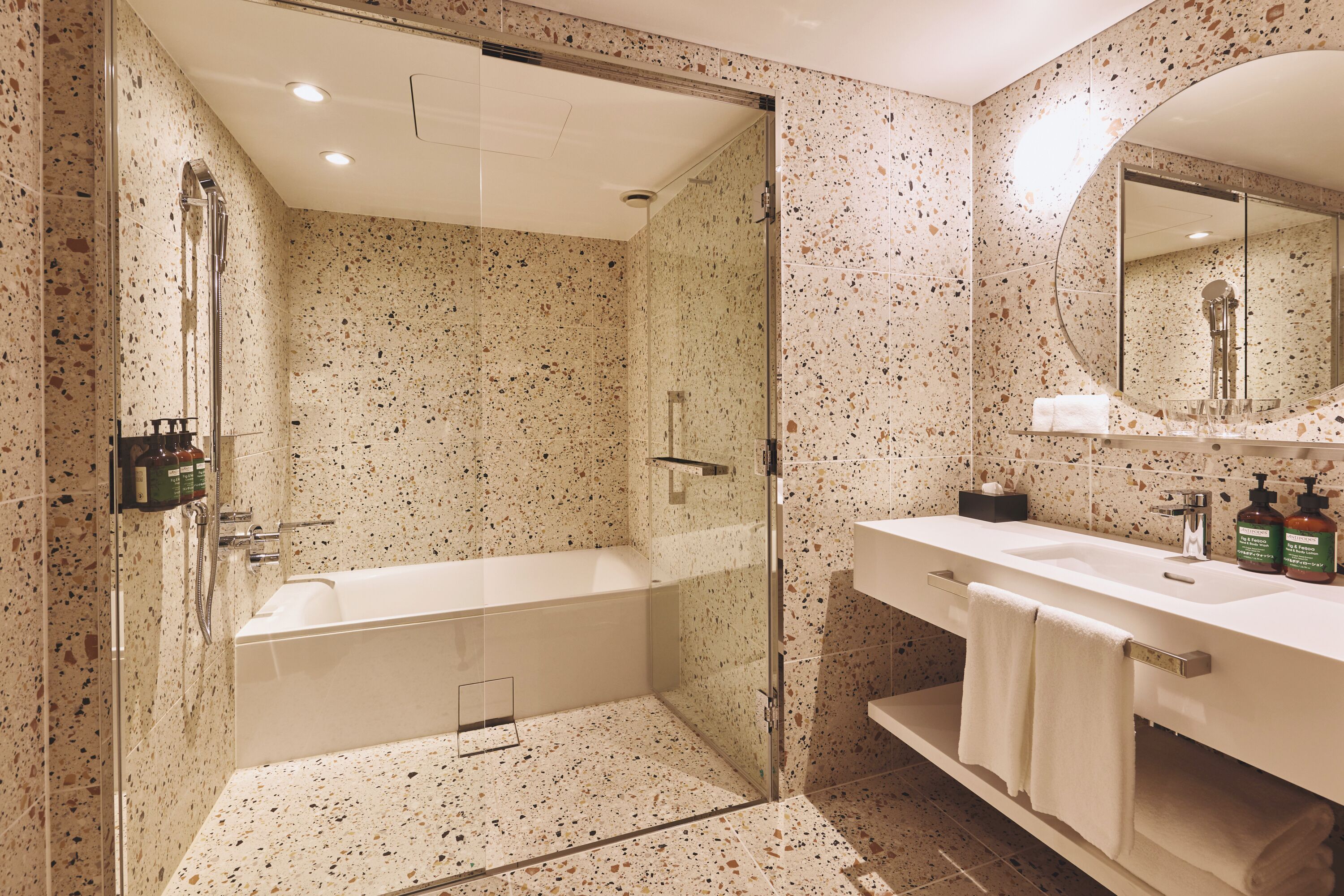 Ein modernes Badezimmer mit einer gläsernen Duschkabine, einer freistehenden Badewanne und einem Waschtisch mit Spiegel.