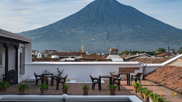 A terrace with outdoor seating and potted plants, overlooking a mountain. - Loft El Chiquito (Antigua Guatemala)