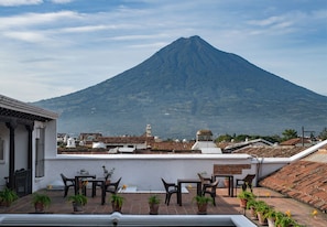 A terrace with outdoor seating and potted plants, overlooking a mountain. - Loft El Chiquito (Antigua Guatemala)