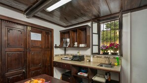 A kitchen with wooden cabinets, a countertop with a toaster, and a window with flowers. - Loft El Chiquito (Antigua Guatemala)