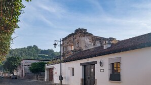 A cobblestone street with historic buildings, a prominent church with a bell tower, and a street lamp. - Loft El Chiquito (Antigua Guatemala)