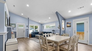 A dining area with a wooden table and chairs, a blue wall, and a window with blinds.