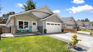 A single-story house with a covered patio, a garage, and a well-maintained lawn.