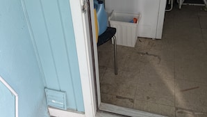 A laundry room with a washing machine, a small stool, and a plastic container.