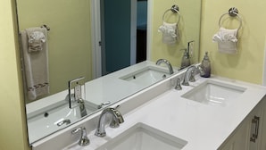 A bathroom with two sinks, a large mirror, and a door leading to another room.