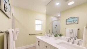 A bathroom with a double sink vanity, a large mirror, and a window.