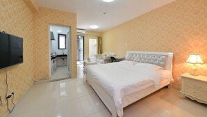 A hotel room with a large bed, a bedside table with a lamp, a TV mounted on the wall, and a bathroom visible through an open door. - Tiantianhui Apartment Hotel (Shenzhen)