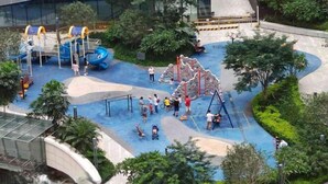 A playground with slides and climbing structures surrounded by greenery. - Tiantianhui Apartment Hotel (Shenzhen)