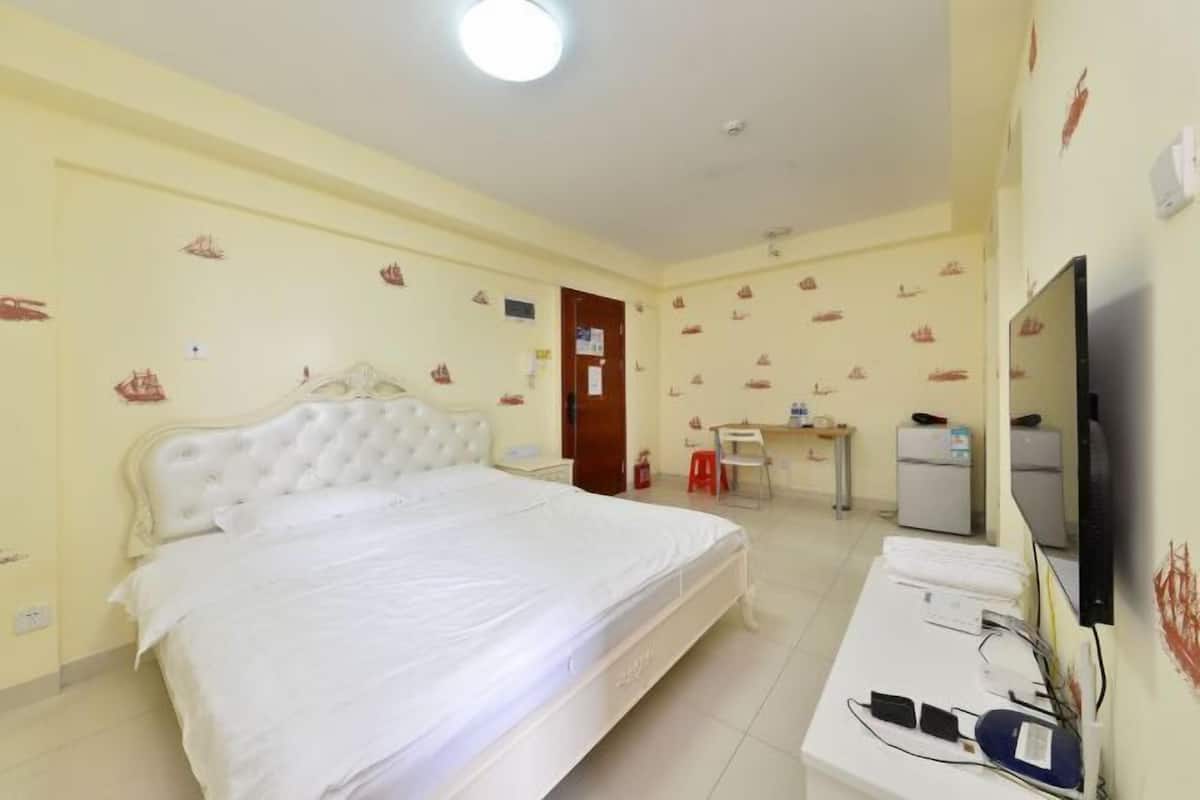 Una habitación de hotel con una cama grande, un escritorio con computadora, una silla y televisión.