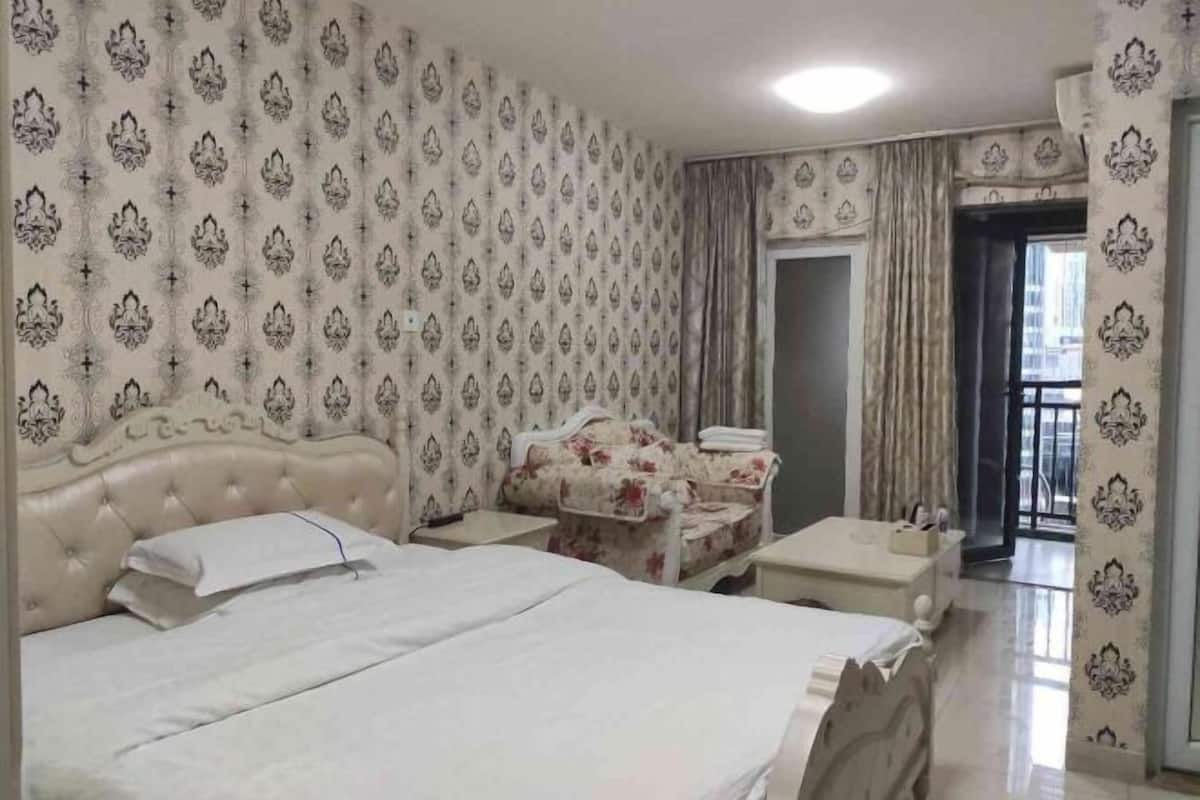 Una habitación de hotel con una cama grande, un sofá, una mesita y un balcón.