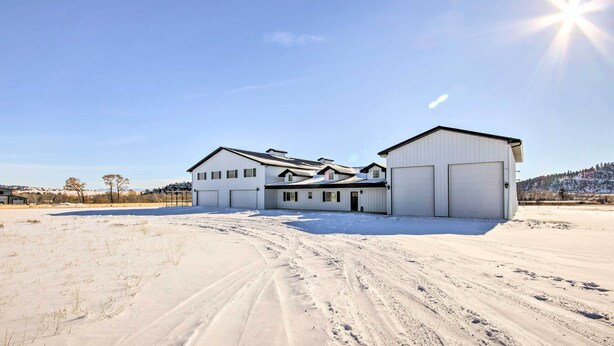 A large, single-story building with a garage and a covered area, surrounded by snow-covered ground and a clear sky.