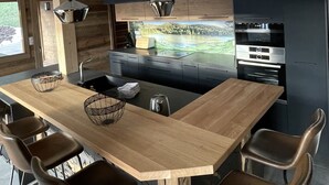 Una cocina moderna con una isla de madera, taburetes de bar y un amplio ventanal con vistas a un paisaje pintoresco.