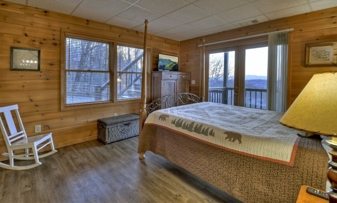 Una habitación acogedora con una cama, una mecedora y una ventana con vistas a las montañas.
