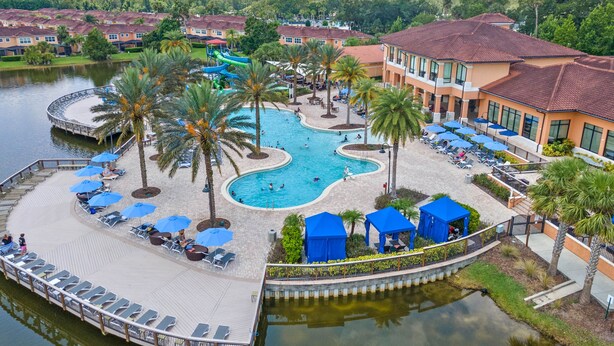 A resort with a large swimming pool, palm trees, and a water slide.