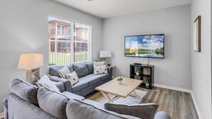 A modern living room with a grey sofa, a coffee table, and a TV on the wall.