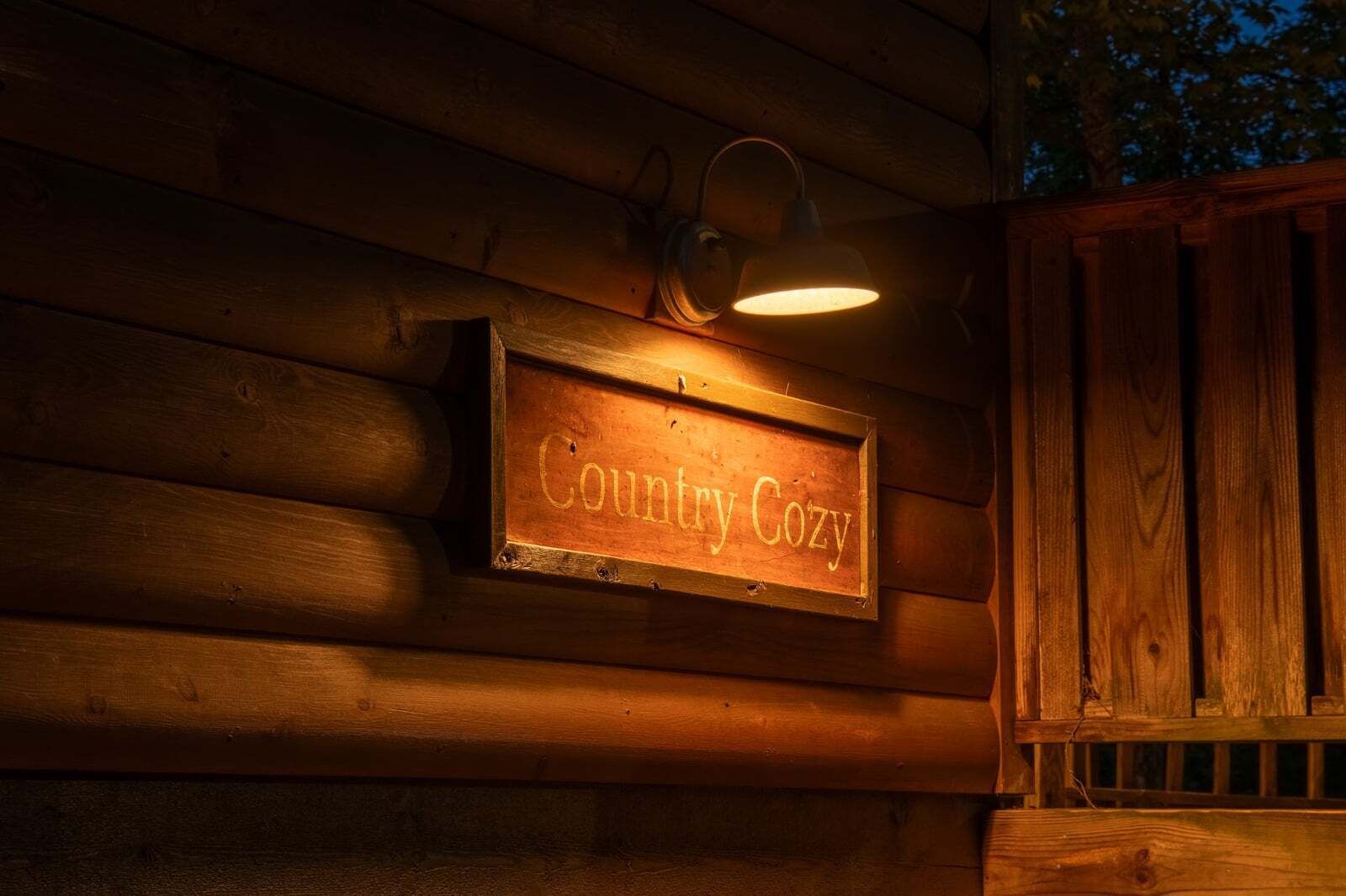 Une cabane en bois avec une enseigne sur laquelle on peut lire « Confort rustique » et une lanterne au-dessus.